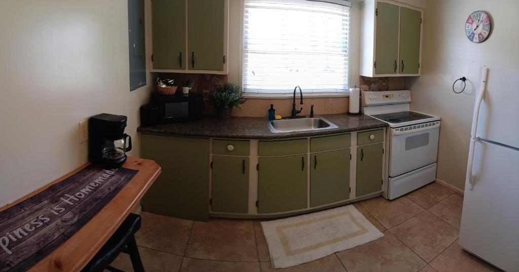 a kitchen with green cabinets and a sink and a refrigerator at Trees Motel in Bishop