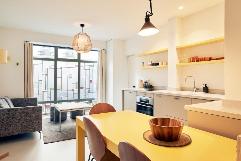une cuisine et un salon avec une table jaune dans l'établissement Grand studio pour 4p Paris 14, à Paris