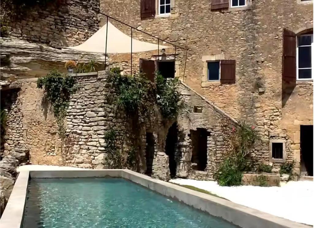 une piscine devant un bâtiment en briques dans l'établissement Maison d exception au coeur de Goult avec piscine privée et vue panoramique, à Goult