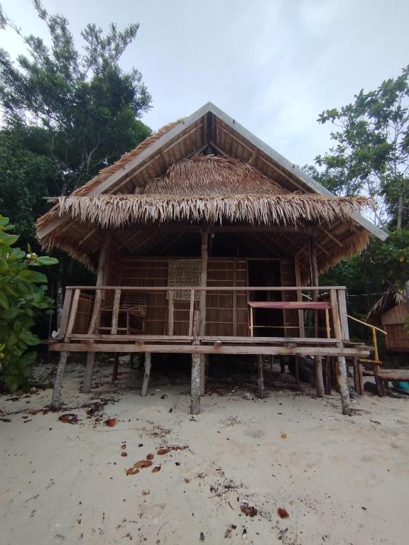 a hut with a straw roof on the beach at Batanta Panorama Homestay in Dayang