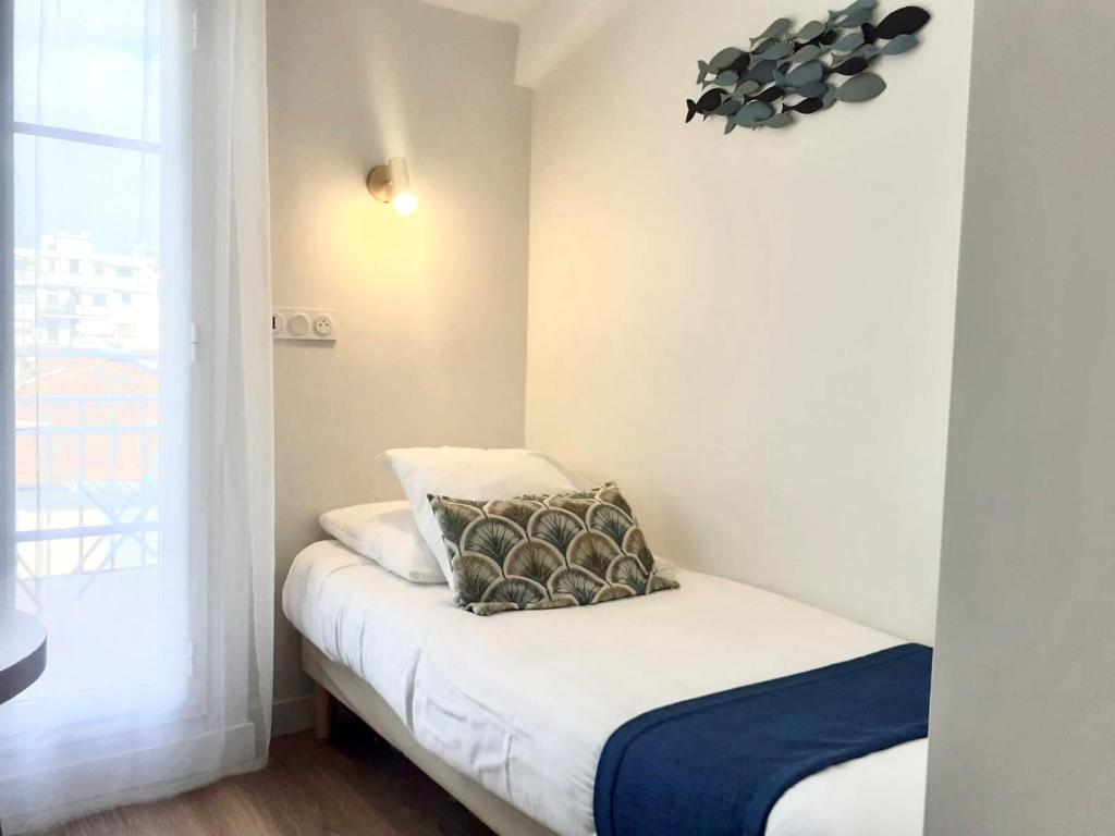 a small bedroom with a bed with a window at Hotel Solara in Nice