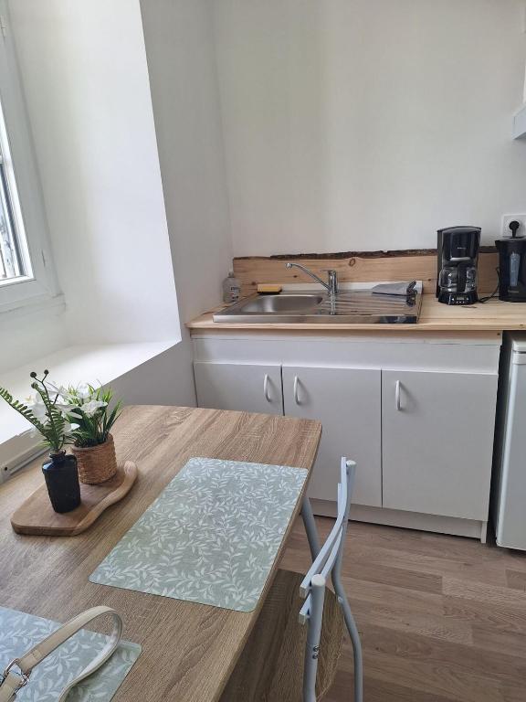 - une cuisine avec un évier et une table en bois dans l'établissement L'Instant Simplicité - Dormir Comme A La Maison, à Châteaubriant