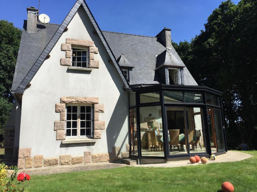 une maison avec de grandes baies vitrées dans la cour dans l'établissement Morlaix - Maison au milieu des bois, à Plourin