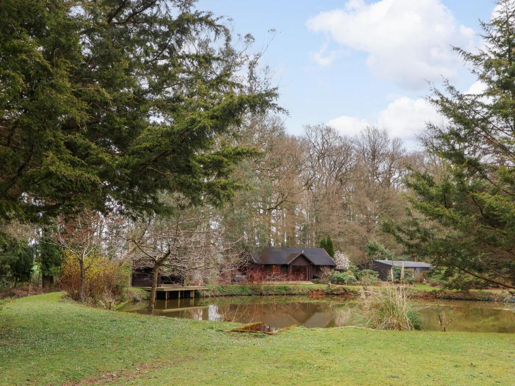 a house in a park with a pond and trees at Woodpeckers in Cullompton