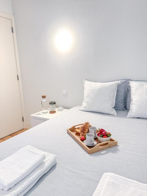 a tray of food on a bed with a plate of food at Room in the Heart of Historic Lisbon on Rua Augusta in Lisbon