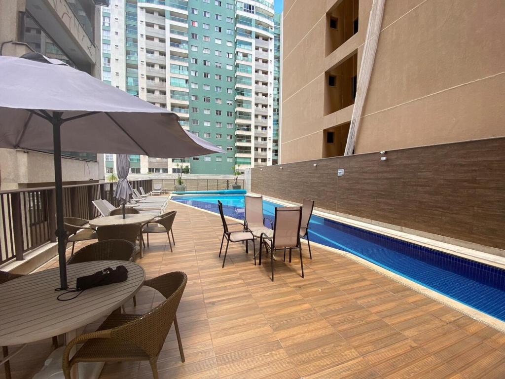 a rooftop patio with tables and chairs and a pool at Via Brisa Apartment in Brasília