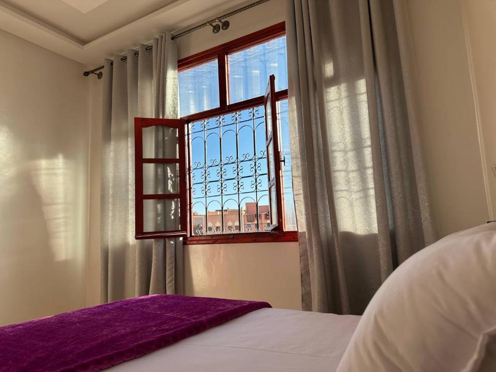 a bedroom with a window and a bed with purple sheets at Residence Dallas Warzazate in Ouarzazate