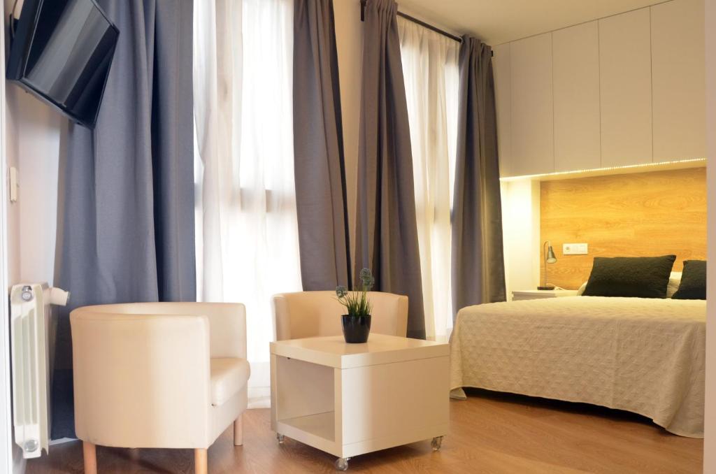 a bedroom with a bed and a chair and a table at Apartamentos Córdoba Atrium in Córdoba