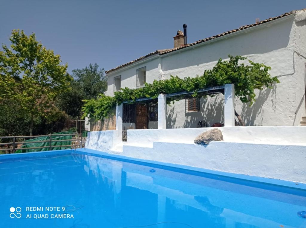 a swimming pool in front of a house at Finca Rústica La Pájara in Iznatoraf
