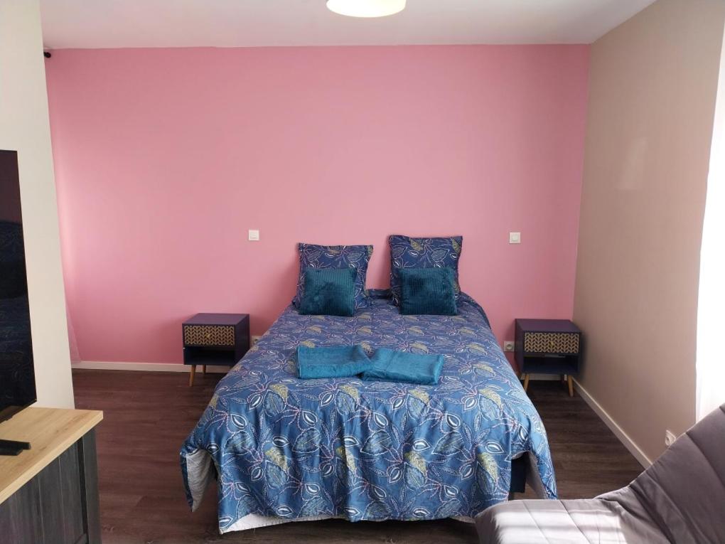 Cette chambre comprend un lit avec des draps bleus et un mur rose. dans l'établissement L olivier, au Mans