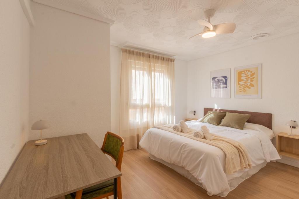 a white bedroom with a bed and a table at El Retiro de Julián in Santa Pola