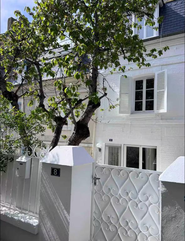 une clôture blanche devant une maison blanche avec un arbre dans l'établissement La Dolce Trouvillaise, à Trouville-sur-Mer