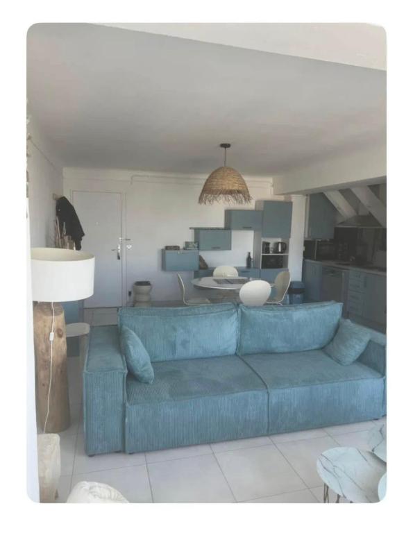 un salon avec un canapé bleu et une cuisine dans l'établissement appartement meuble vue sur le port, à Canet