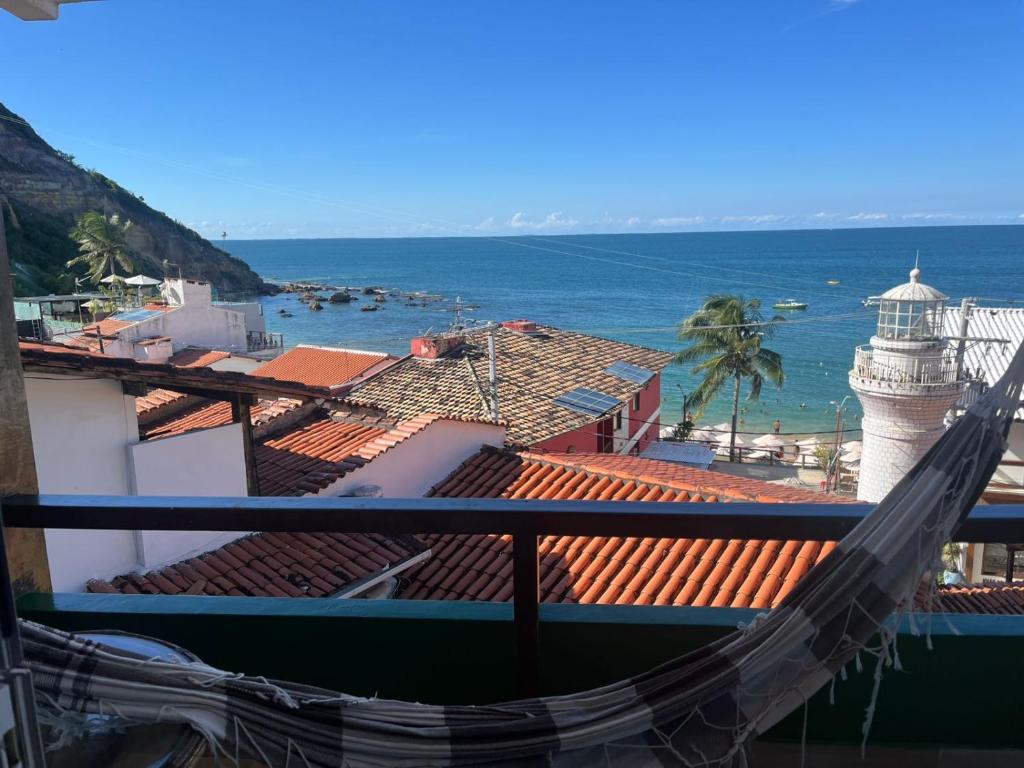 a view of the ocean from a balcony with a lighthouse at Pousada Farol do Morro in Morro de São Paulo