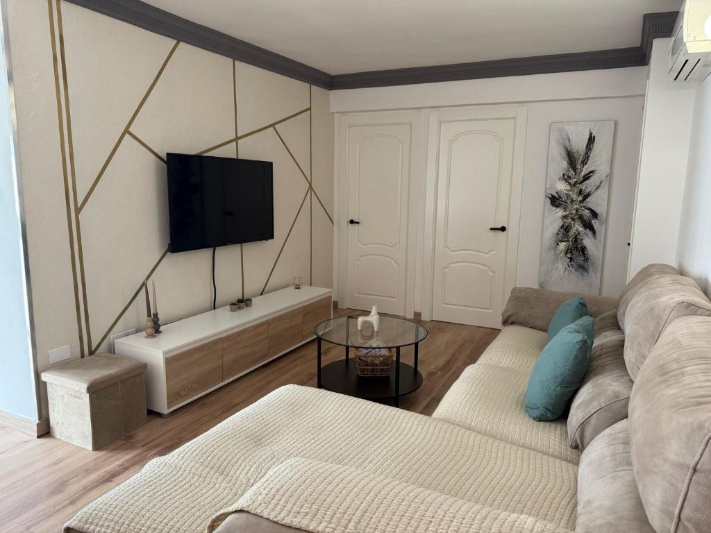 Una sala de estar con un sofá y un televisor en una pared. en Ámplio piso en el corazón de Torremolinos, en Torremolinos