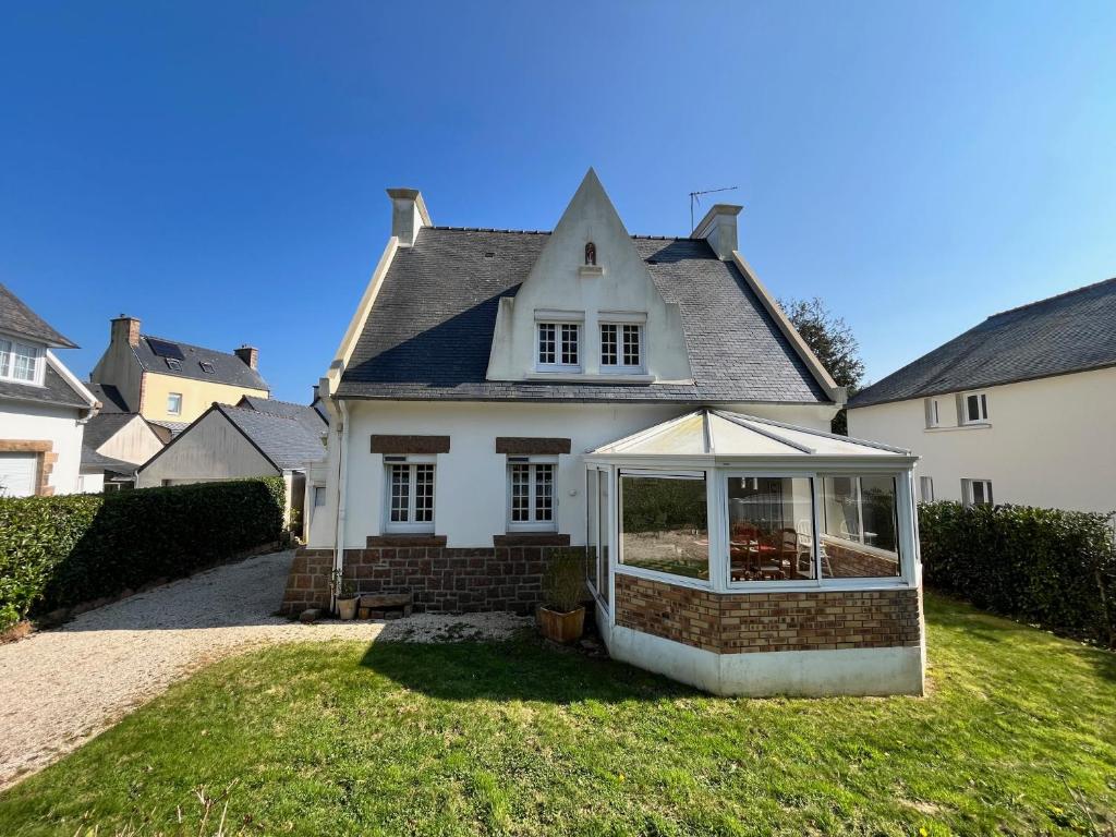 une maison blanche avec une véranda dans la cour dans l'établissement MAISON CENTRE VILLE 3 CHAMBRES 6 ou 8 PERS PROCHE PLAGE ET JARDIN CLOS, à Perros-Guirec