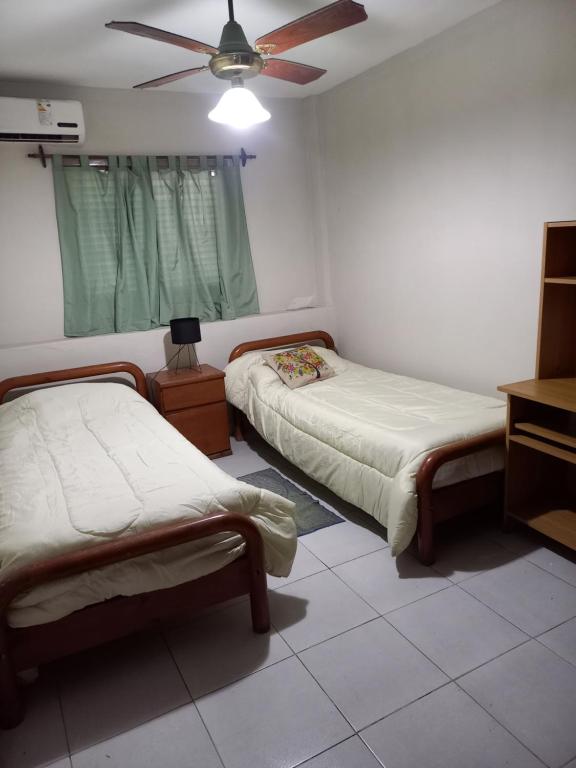 ein Schlafzimmer mit zwei Betten und einem Deckenventilator in der Unterkunft America in San Miguel de Tucumán
