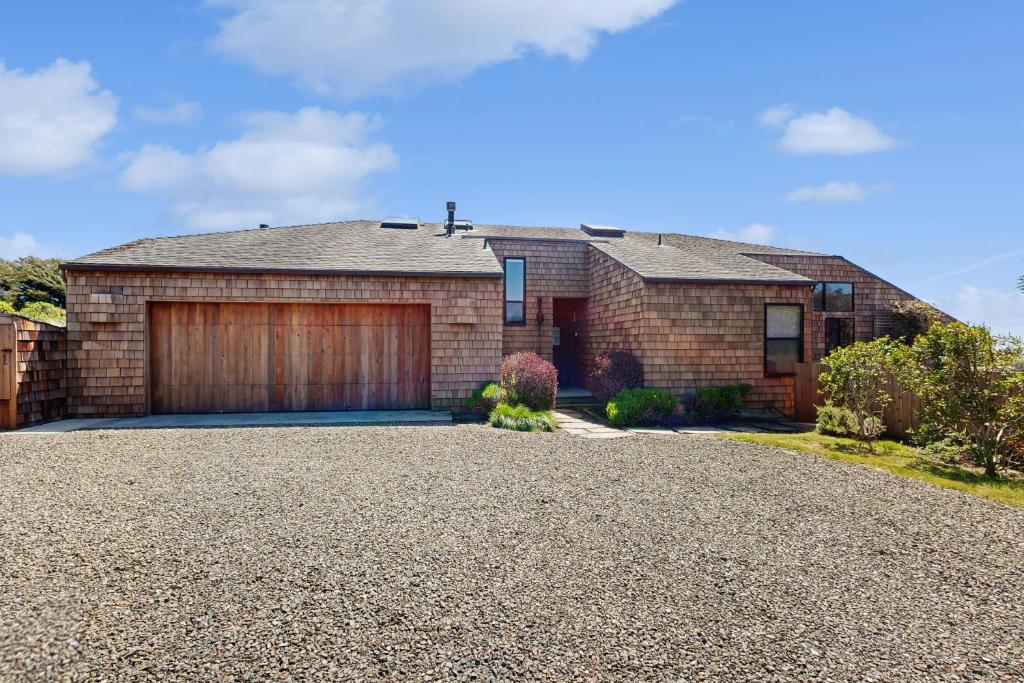 a brick house with a garage on a gravel driveway at Cadwalader House in Sea Ranch