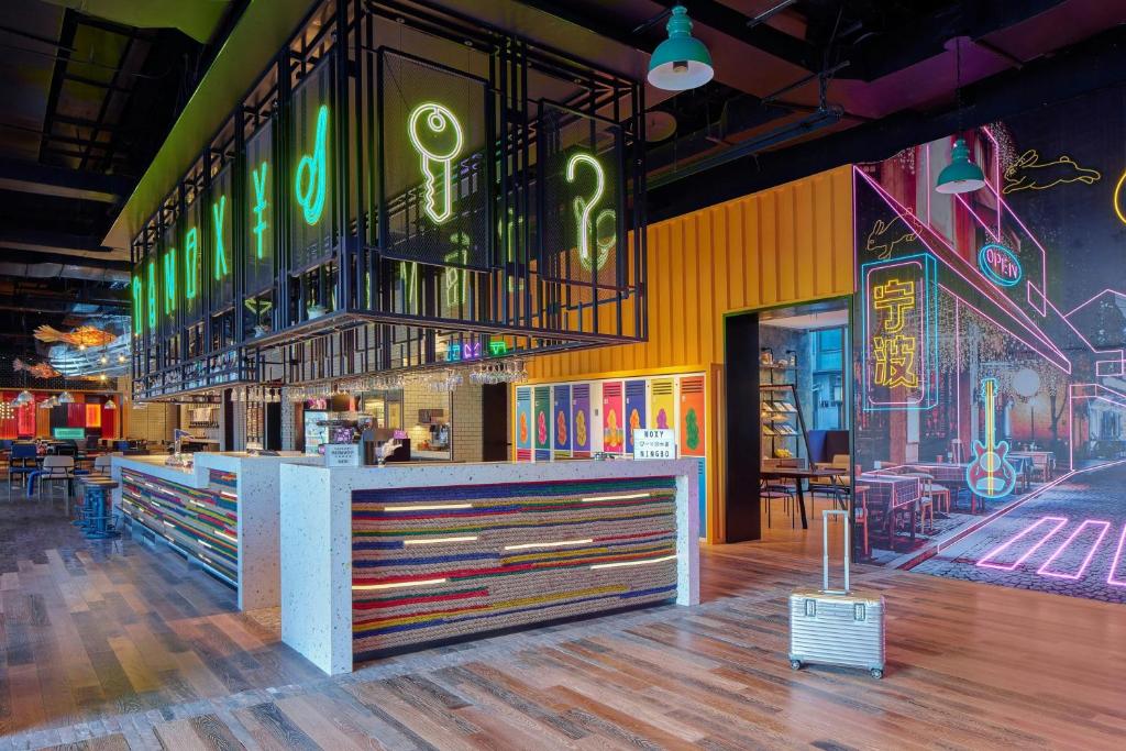 a restaurant with a counter with neon signs on the wall at Moxy Ningbo Old Bund in Ningbo