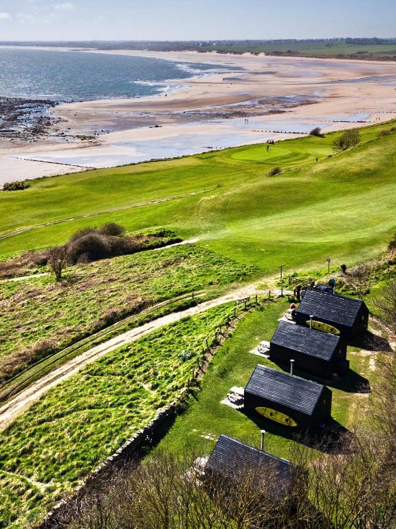 a group of picnic tables on a hill next to the beach at St Hilda Beach Hut Alnmouth in Alnmouth