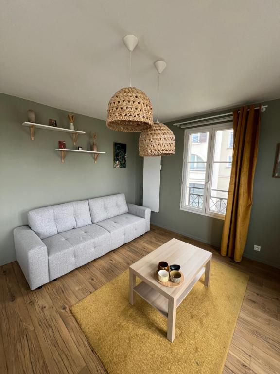 un salon avec un canapé blanc et une table dans l'établissement Cosy Home, à Magny-le-Hongre