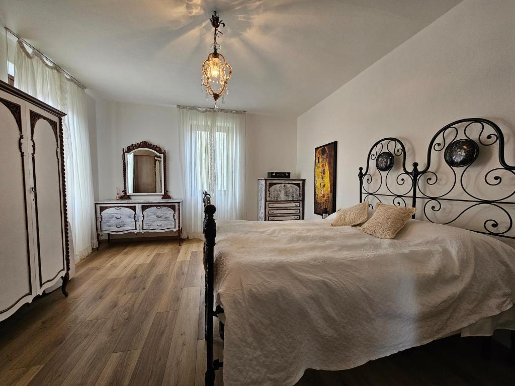 sypialnia z dużym łóżkiem i żyrandolem w obiekcie VILLA LAGO foreground - Pet friendly stay- garden-parking-Lake view- Bike friendly holiday house w mieście Colico