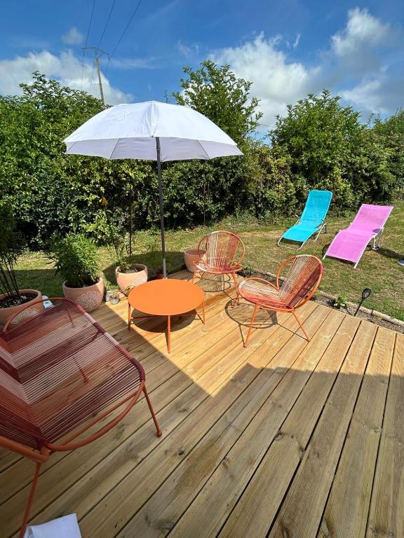 un patio avec une table, des chaises et un parasol dans l'établissement Le Cocoon de la Héronnière, à Houlle