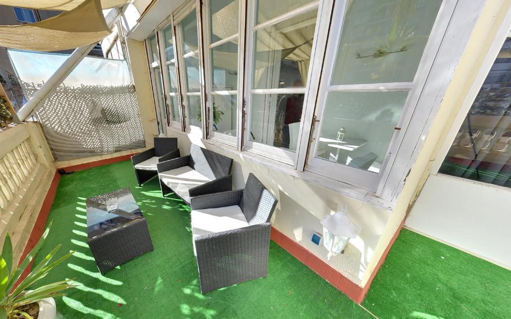 Habitación con suelo verde y sillas en el balcón. en Des Artistes, en Barcelona