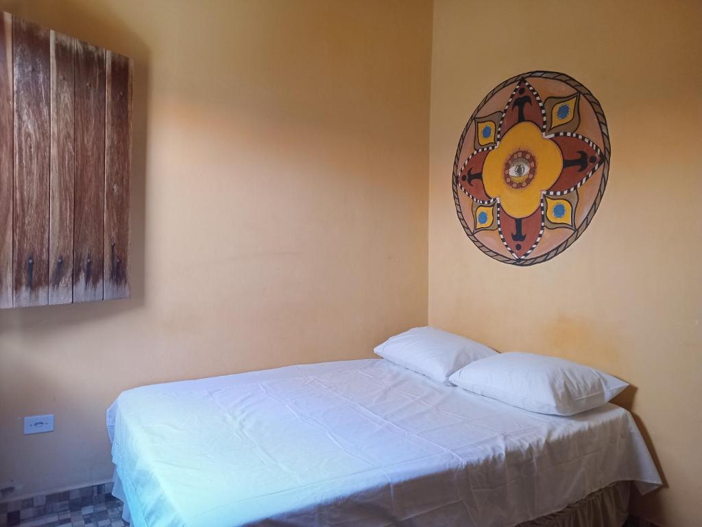 a bedroom with a bed and a picture on the wall at Quarto para 4 com banheiro privado a 900 metros da Vila do Capão in Vale do Capao