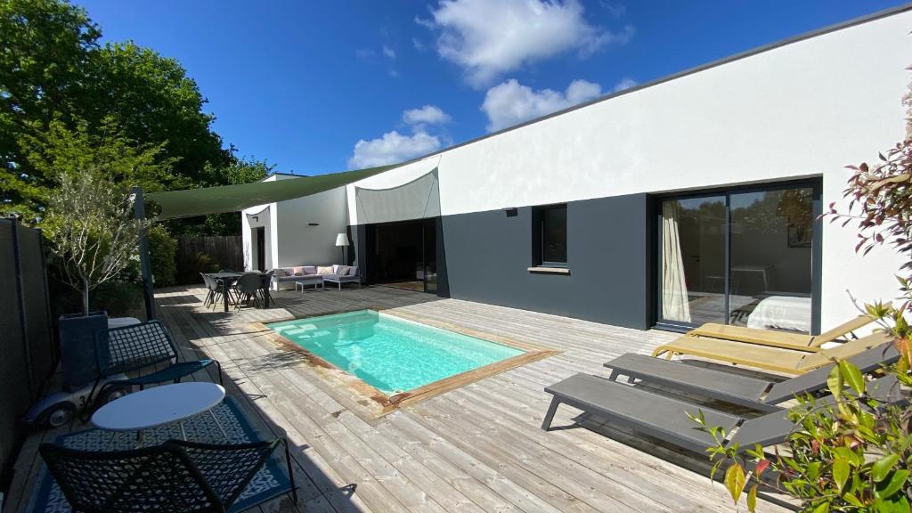 une terrasse avec une piscine et une maison dans l'établissement Villa des Pins, à Andernos-les-Bains