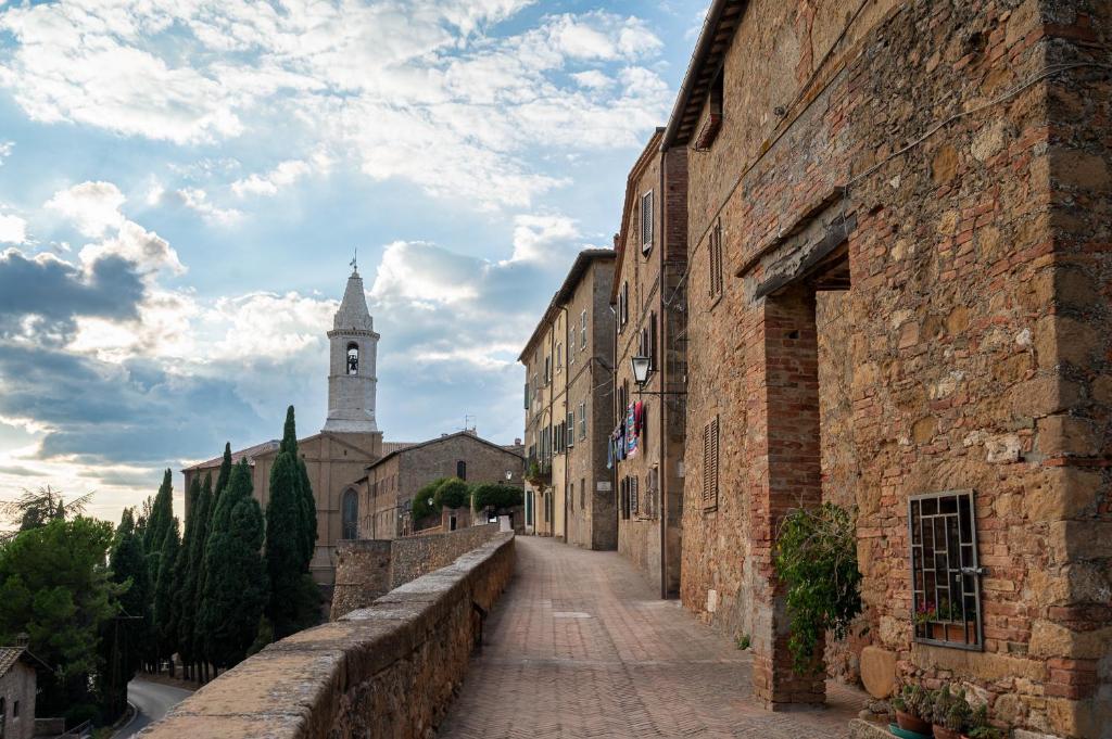an alley in an old town with a clock tower at Artistica Pienza - Breathtaking Val d'Orcia View in Pienza