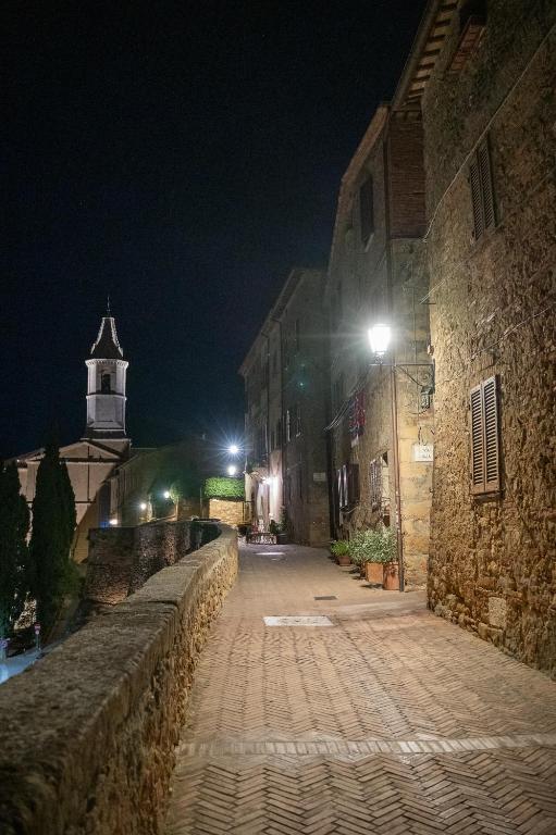 an empty street at night with a lighthouse in the background at Artistica Pienza - Breathtaking Val d'Orcia View in Pienza