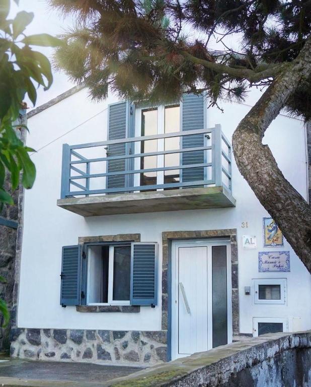 a white house with blue windows and a balcony at Casa Mamã e Papá in Mosteiros