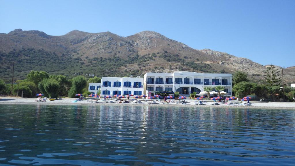 a beach with white buildings and chairs and the water at Hotel Eleni Beach in Livadia