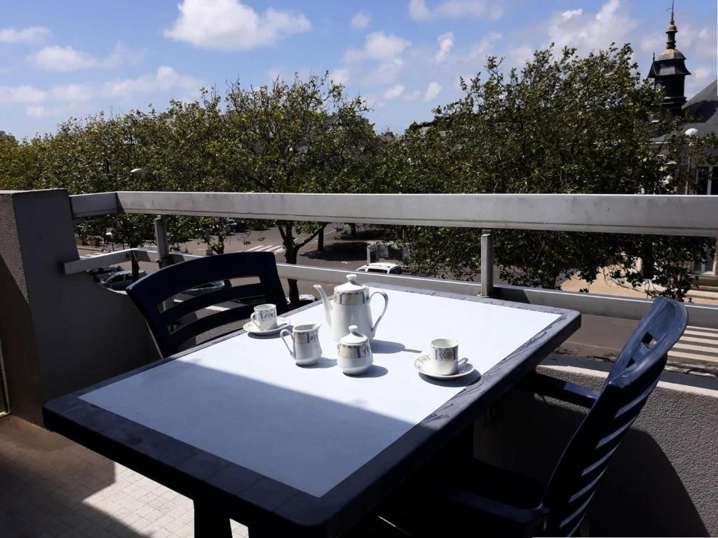 une table avec des tasses et des tasses sur un balcon dans l'établissement Résidence Le Renaissance - Pornichet - Studio Place du Marché MAE-6571, à Pornichet