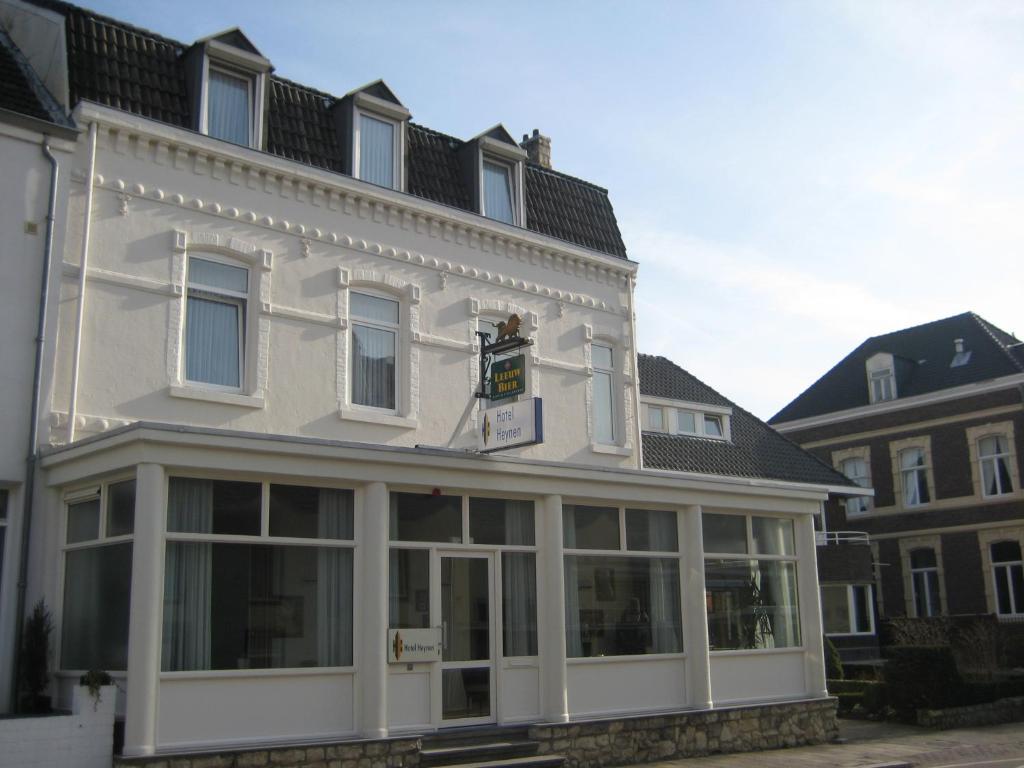 ein weißes Gebäude mit großen Fenstern auf einer Straße in der Unterkunft Hotel Heynen in Valkenburg