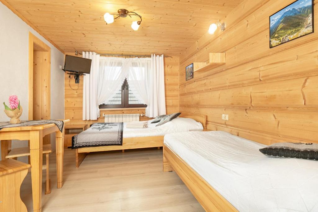 a bedroom with two beds in a wooden cabin at Willa Emilia in Zakopane