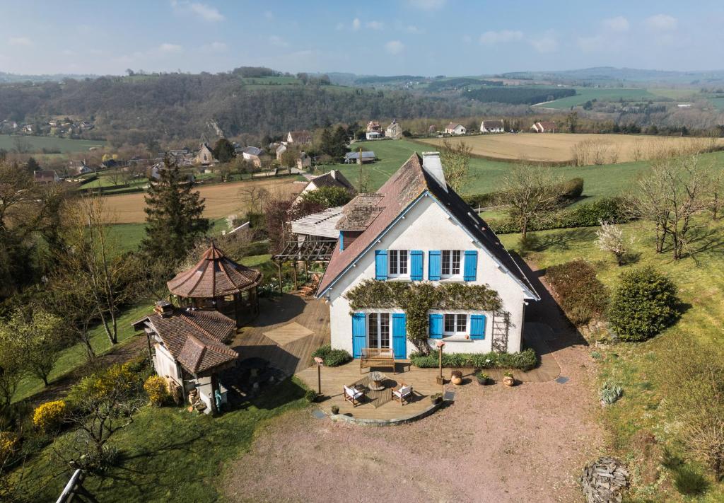 une vue aérienne d'une maison blanche aux volets bleus dans l'établissement VillaNona, à Saint Remy sur Orne
