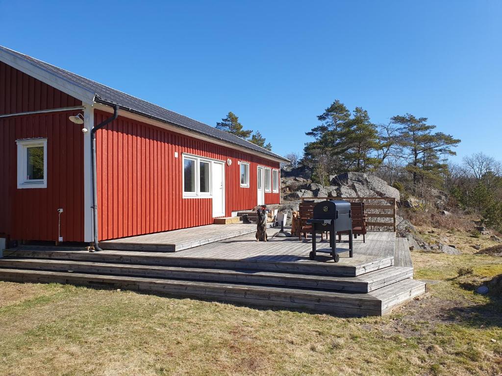 un edificio rojo con una terraza de madera delante de él en Stugan Hultet, en Hjälteby