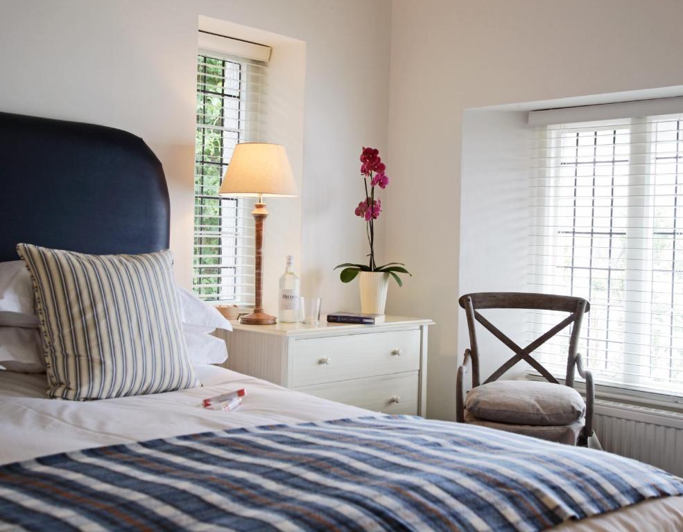a bedroom with a bed and a chair and windows at Cary Arms & Spa in Torquay