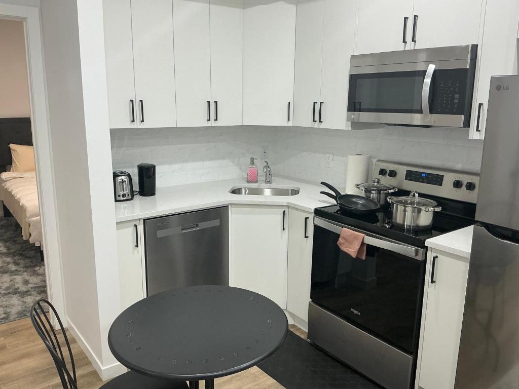 cocina con armarios blancos y fogones negros en Home sweet home, en Calgary