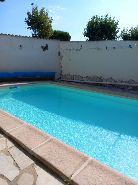 une piscine d'eau bleue devant un mur blanc dans l'établissement Villa avec piscine côté mer, à Palavas-les-Flots