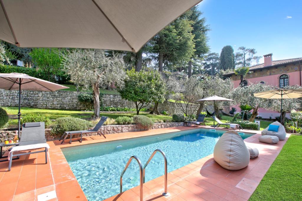 a swimming pool with chairs and umbrellas in a yard at Villa Schlosser Lake Front & Private Pool in Malcesine