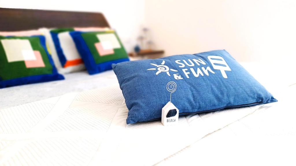 a pillow with a sun and fun written on it on a bed at Appartamento Conchiglia Blu di Pietra in Pietra Ligure