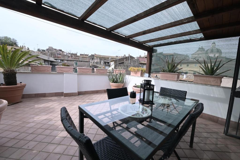 un tavolo in vetro e sedie su un patio di Ronciglione Home di F & E a Ronciglione