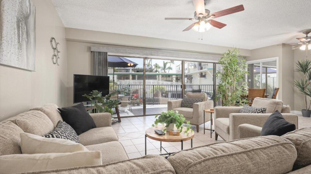 a living room with a couch and chairs and a tv at Hale Lopaka at Kona Plaza in Kailua-Kona