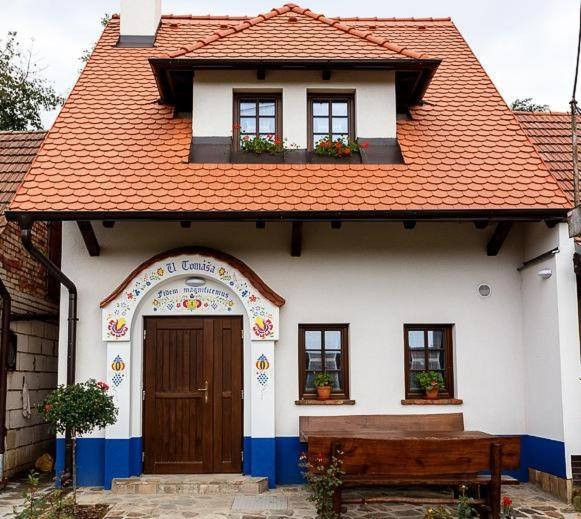ein weißes Haus mit einer Holztür und einer Bank in der Unterkunft Sklipek U Tomáša in Hovorany