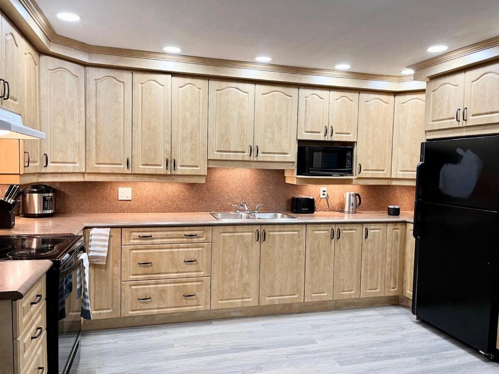 a kitchen with wooden cabinets and a black refrigerator at Charming beautiful house 7mn to downtown Ottawa in Gatineau