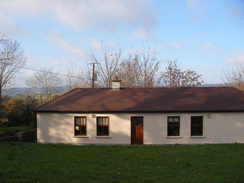 una pequeña casa blanca con techo marrón en Mountshannon cottage, en Mountshannon