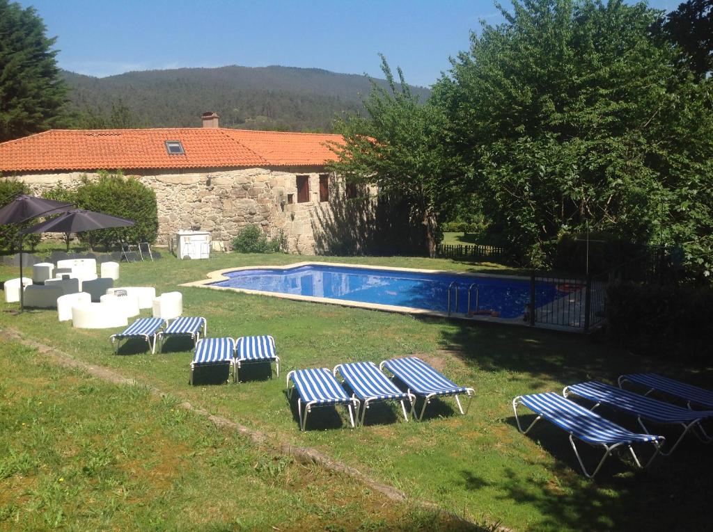 - un groupe de chaises longues installées à côté de la piscine dans l'établissement Pazo Larache, à Santa Cristina de Cobres